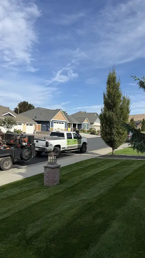Abel's & Sons trucks and equipment trailer at the curb beside a freshly striped front lawn