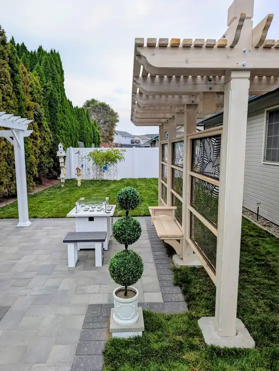 Finished grey paver patio with a white vinyl pergola and fresh lawn